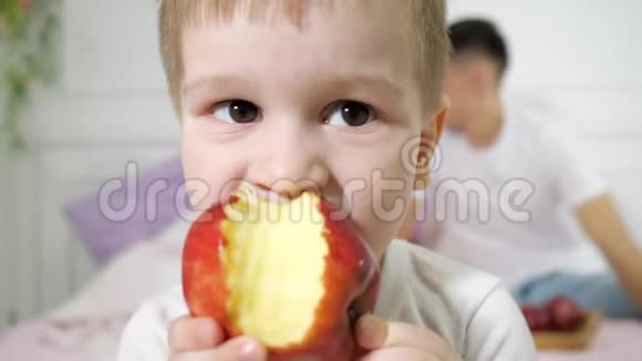 小男孩正在父母卧室里吃苹果他的父母坐在床上视频的预览图