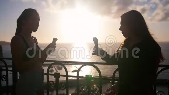 两个年轻会说话的女人站在码头上在日落时分吃冰淇淋视频的预览图