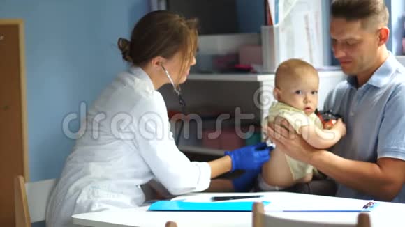 父亲和他的孩子在儿科医生约会一位女医生检查一个一岁半的小男孩视频的预览图