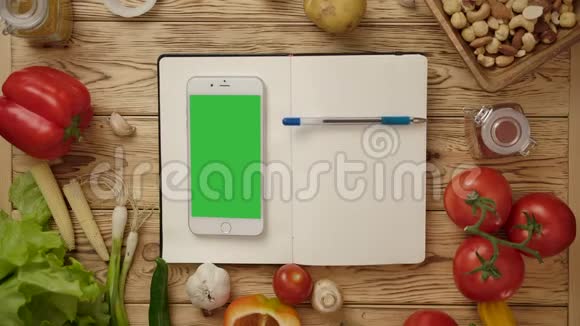笔在空白笔记本上滚动智能手机在厨房桌上放蔬菜视频的预览图