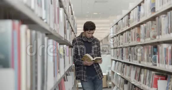大学生站在图书馆的地板上看书垂直形状侧视中射视频的预览图