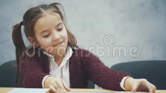 快乐可爱的聪明女孩坐在桌子上的一叠书和笔记本电脑的肖像复制空间教育与发展视频的预览图