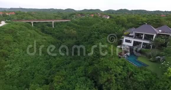 巴厘岛的空中镜头覆盖着绿树别墅和一座大桥4k视频的预览图
