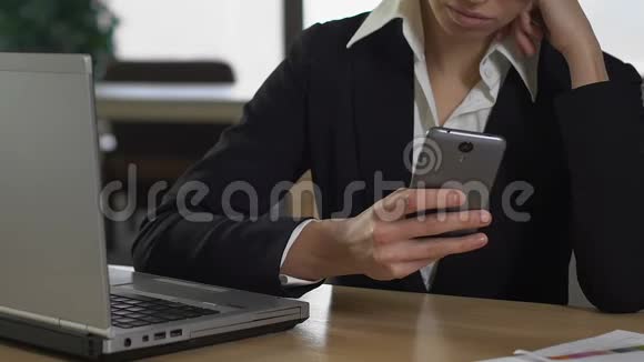 女办公室职员坐在笔记本电脑前的智能手机上聊天技术视频的预览图