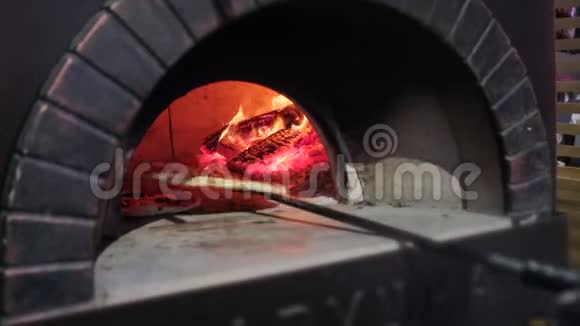 厨师把生披萨放在披萨店的砖烤箱里视频的预览图