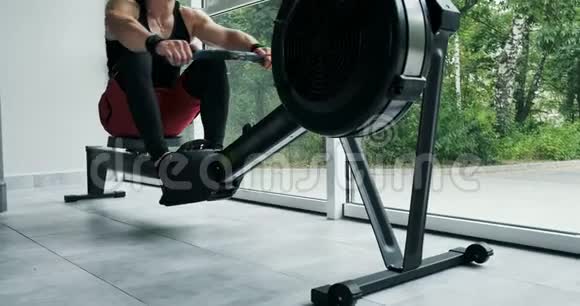 强壮的肌肉男在室内划船模拟器上工作健身房交叉健身训练视频的预览图