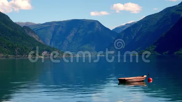 停泊在一个红色浮标上的小木船漂浮在挪威的Lustrafjord水域有群山的倒影蓝天视频的预览图