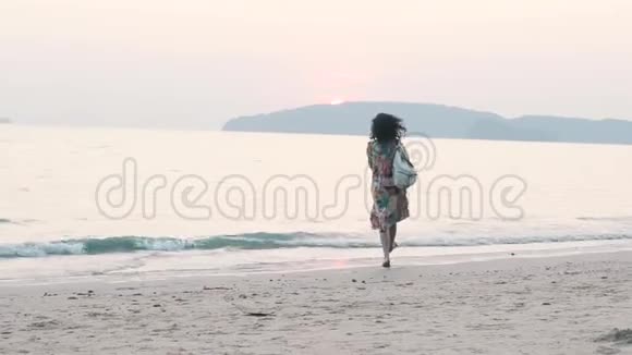 带背包的女孩在日落时在海滩上玩得很开心视频的预览图