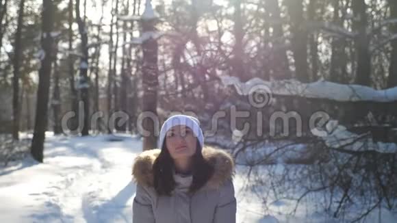 年轻快乐的女人穿着冬天的衣服扔一把雪享受飘落的雪花有魅力的女孩视频的预览图
