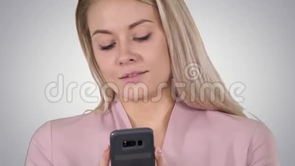 时髦的微笑金发女人使用她的手机微笑当她键入一个短信梯度背景视频的预览图
