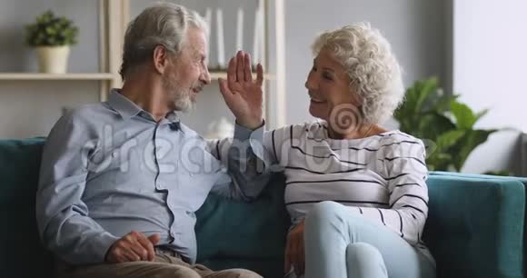 快乐的老爷爷奶奶夫妇放松谈话笑坐在沙发上视频的预览图