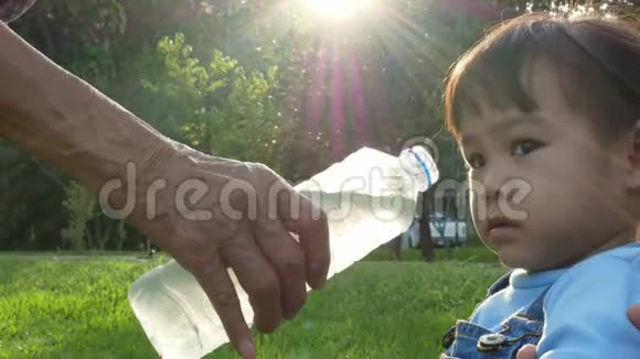 小亚洲女孩在花园里喝瓶子里的水视频的预览图