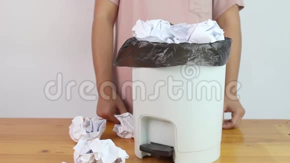 亚洲女人把皱巴巴的纸收到一个黑色的垃圾袋里装在垃圾桶里等待回收概念保存视频的预览图