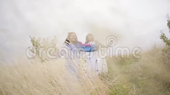 三个女朋友穿着漂亮的夏装刺绣在田野里跳跃穿过田野视频的预览图