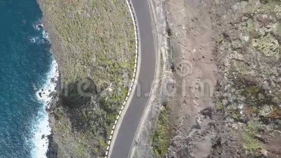 在西班牙特内里费空中无人机拍摄的一条公路沿着垂直悬悬在海洋上的悬崖蓝色的俯视图视频的预览图
