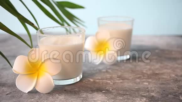 一杯椰奶配花梅球和摇摆的棕榈叶视频的预览图