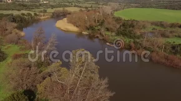 在撒丁岛环绕着树木和农田俯瞰湖和科希纳斯河的空中景色视频的预览图