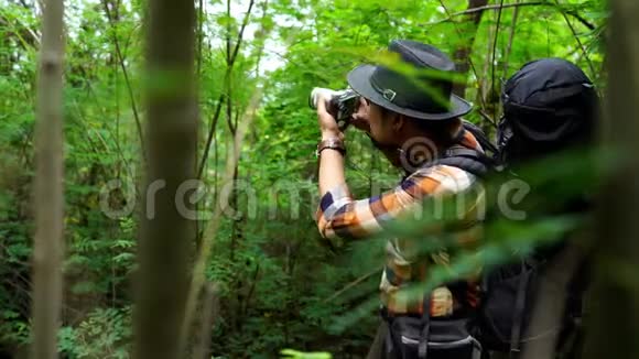 带背包的人用照相机在天然森林里拍照视频的预览图