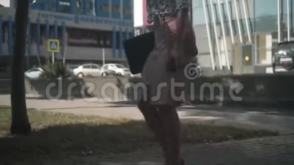 商务女性穿着一件白色衬衫上面有黑豌豆手里拿着一台笔记本电脑走在街上打电话视频的预览图