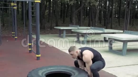 强壮的年轻人在户外运动时翻轮胎交叉配合视频的预览图