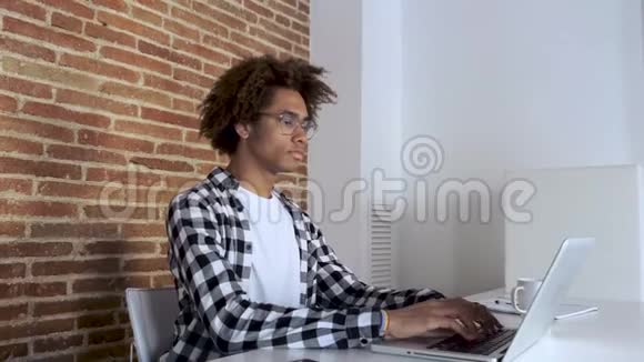 一位年轻的美国黑人青年在家工作时戴着眼镜伸展身体视频的预览图
