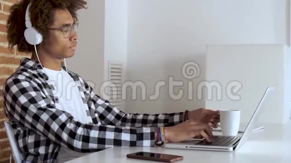 英俊的美国黑人年轻人在家里拿着笔记本电脑一边喝咖啡视频的预览图