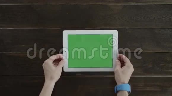 一个人把桌子放在有绿色屏幕的木桌上视频的预览图