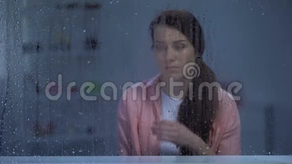 哭泣的中年妇女透过雨窗寻找生活和健康问题视频的预览图