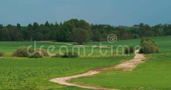 在阳光明媚的温暖的日子里桑迪蜿蜒的乡间小路小径穿过春天的草地空气从热中融化视频的预览图