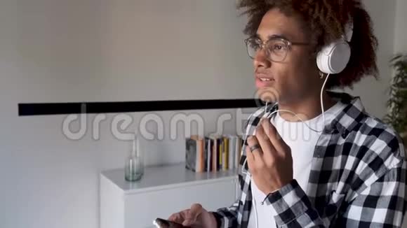英俊的非裔美国年轻人手拿免费手机在家交谈视频的预览图