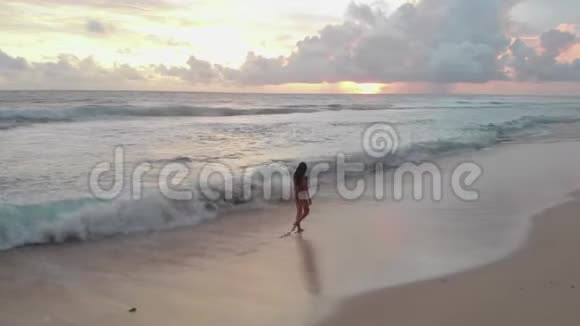 一个穿泳衣的女孩沿着沙滩散步视频的预览图
