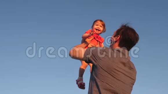爸爸把孩子扔在蓝天上爸爸和一个小女儿玩宝宝笑着高兴慢动作视频的预览图