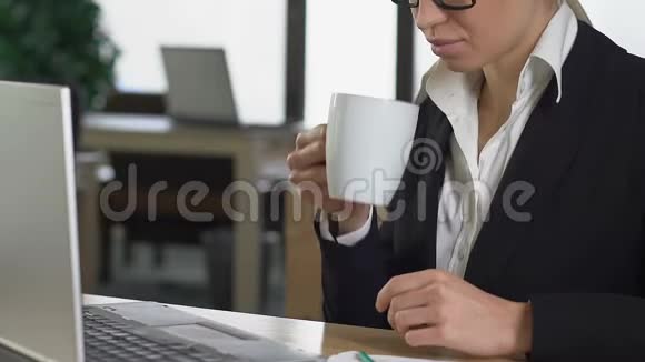 精力充沛的年轻女性穿着西装喝着咖啡手提电脑视频的预览图