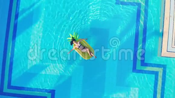 夏季旅游概念年轻女子在黄色床垫上放松漂浮在游泳池里视频的预览图