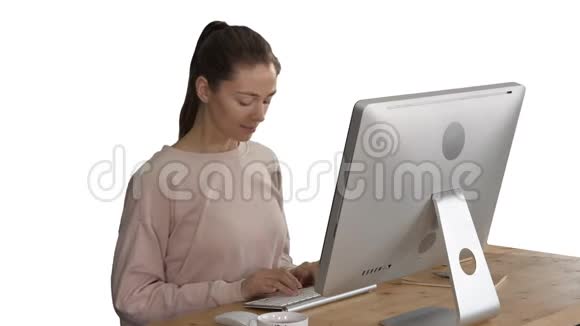 快乐轻松的年轻女子坐在电脑前伸展白色背景视频的预览图