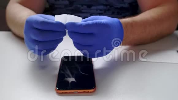 男性手中的蓝色手套取代了一个破碎的钢化玻璃屏幕保护器的智能手机一个男人准备智能手机视频的预览图