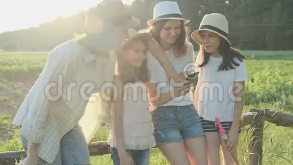 幸福的母亲带着三个女儿看着智能手机家庭的本质视频的预览图