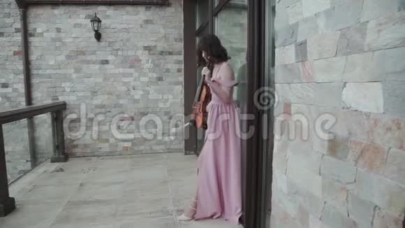 热情的女人在阳台上拉小提琴视频的预览图