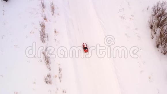 橙色的汽车正沿着一条冬天下雪的乡村道路行驶从无人驾驶飞机上俯瞰视频的预览图
