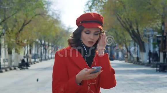 优雅的年轻女孩穿着红色外套在街上自由跳舞很愉快视频的预览图