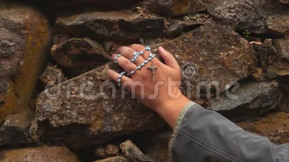 石墙上戴着念珠的手臂视频的预览图
