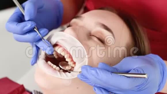 一位牙科检查人员对女孩面部进行了一次特写检查他张开嘴用餐巾纸和闭眼牙医视频的预览图