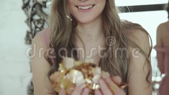 快乐的金发女郎微笑着对着镜头吹金色的包装纸视频的预览图