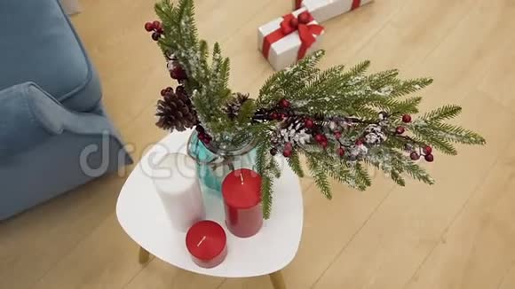 圣诞云杉树枝插在花瓶里装饰着美丽的玩具站在红烛间的桌子上视频的预览图