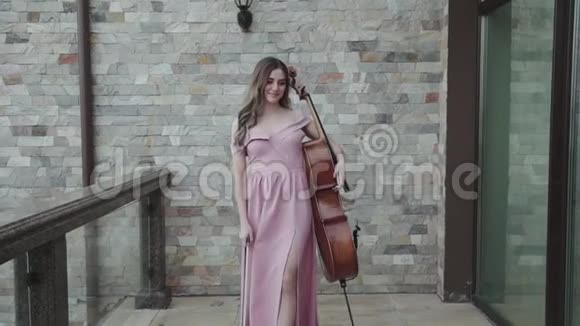 快乐的女大提琴手走在阳台上在大提琴上演奏视频的预览图