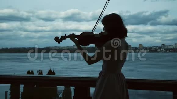 优雅的小提琴家在阳台上优美的背景下的剪影视频的预览图