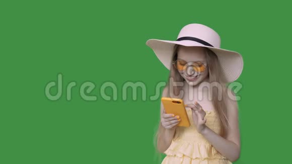 快乐少女浏览智能手机夏季服装和帽子阿尔法频道视频的预览图