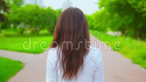 迷人的女孩头发飘摇漫步在春天公园视频的预览图