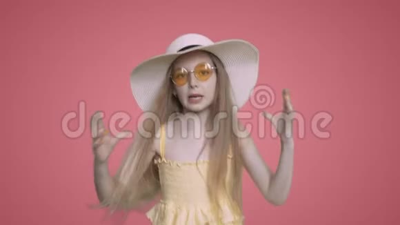 穿着黄色连衣裙和帽子的女孩子正在跳舞在粉红色的背景上唱歌视频的预览图