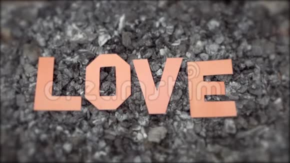 在炎热的烟煤上铭文的爱情是由纸上剪下的字母组成的一阵风把信吹飞视频的预览图